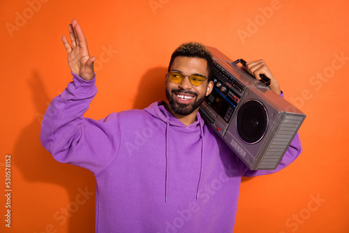 Photo of carefree positive person carry boombox listen music dance isolated on orange color background
