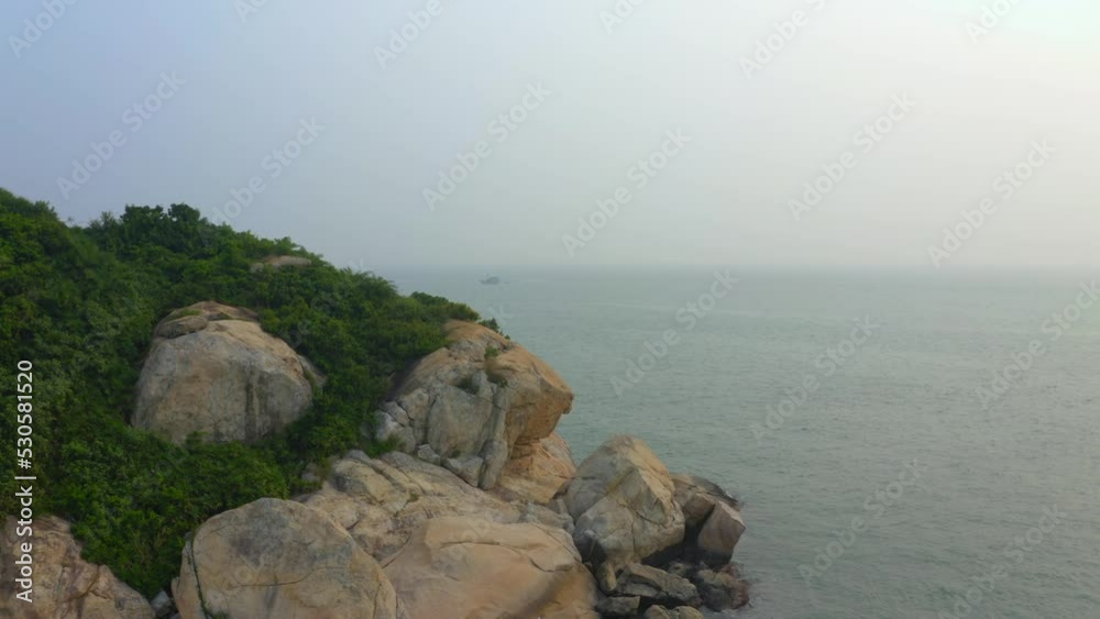 Drone shot of a rocky coast during a very polluted day while a fisherman is fishing. Drone shot of a rocky coast during a very polluted day while a fisherman is fishing.