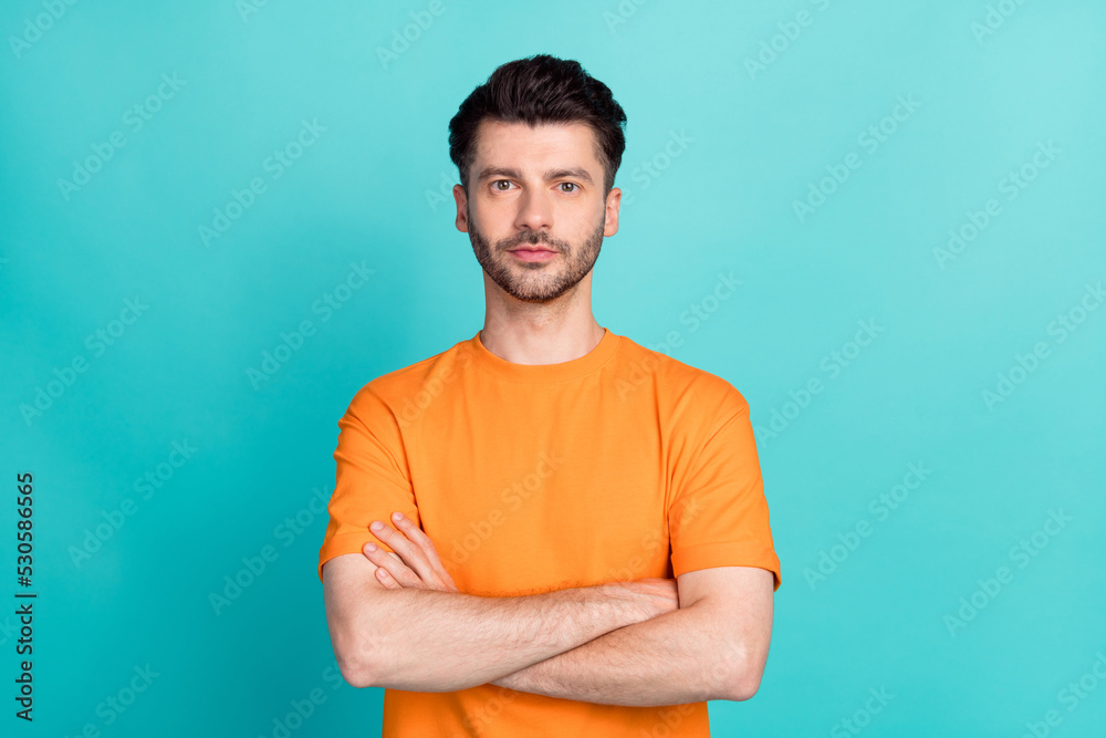 Portrait photo of young handsome serious man student wear orange t-shirt folded hands professional programmer business isolated on cyan color background Portrait photo of young handsome serious man student wear orange t-shirt folded hands professional programmer business isolated on cyan color background
