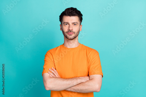 Portrait photo of young handsome serious man student wear orange t-shirt folded hands professional programmer business isolated on cyan color background