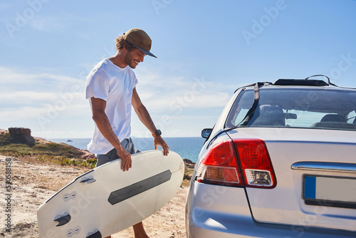 Foto Young surfer holding his bodyboard near the car at the ocean shore