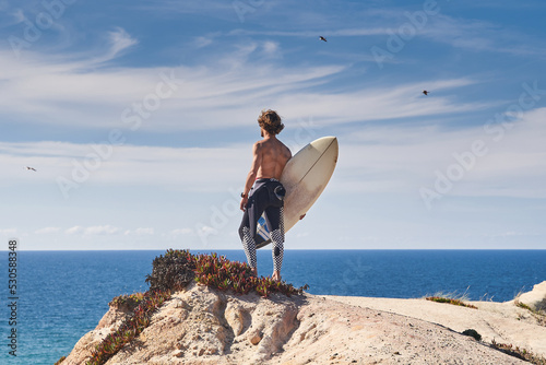 Active young surfer holding surfboard at the beach