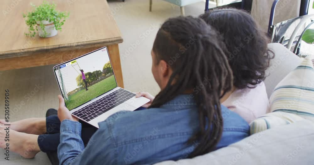 Video of two african american people sitting on the couch and watching football match on laptop Video of two african american people sitting on the couch and watching football match on laptop