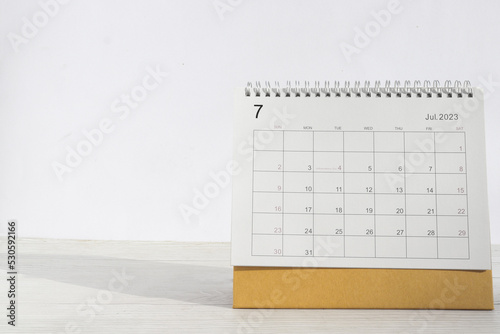 july 2023 Desktop calendar for planners and reminders on a wooden table on a white background.