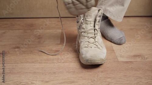 Man puts on brown shoes. Tourist putting on hiking boots