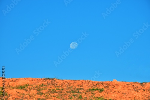 Full moon in beautiful blue cloudy sky in early morning.