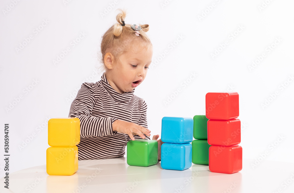 Cute little girl plays with blocks on a white background Cute little girl plays with blocks on a white background