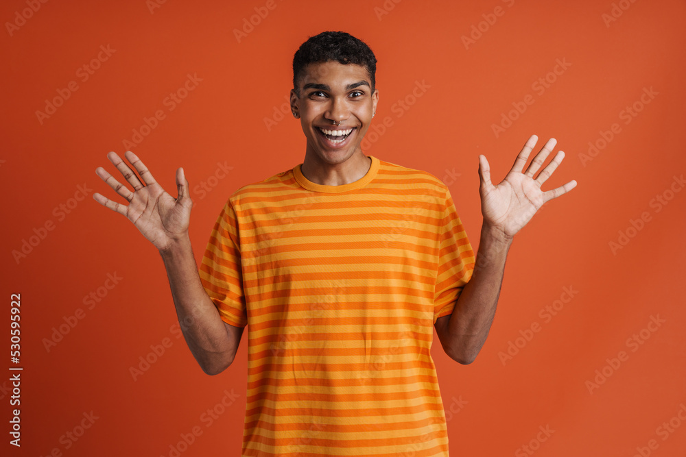 Naklejka premium Young handsome enthusiastic african man with piercing with raised hands