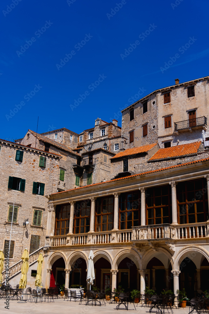 old brick town with a restaurant terrace in the foreground and old, traditionel houses in Sibenik, Croatia