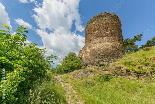 Obraz na płótnie Rabstejn nad Strelou, Czech Republic - June 12 2022: View of the stone tower, a part of the former Sychrov castle, standing on a steep hill. Green grass, footpath leading up. Sunny summer day. w salonie