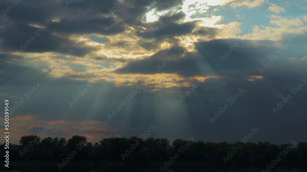 Sun rays shine through the clouds over the forest against a overcast sky. Clouds fly in the sky over Ukraine nature landscape. Weather change Sun rays shine through the clouds over the forest against a overcast sky. Clouds fly in the sky over Ukraine nature landscape. Weather change