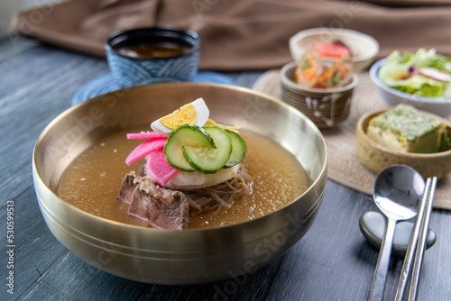 Korean traditional style naengmyeon cold noodles and various fresh vegetable side dishes