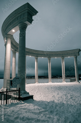 Beautiful white rotunda on the shore of the pond in the evening