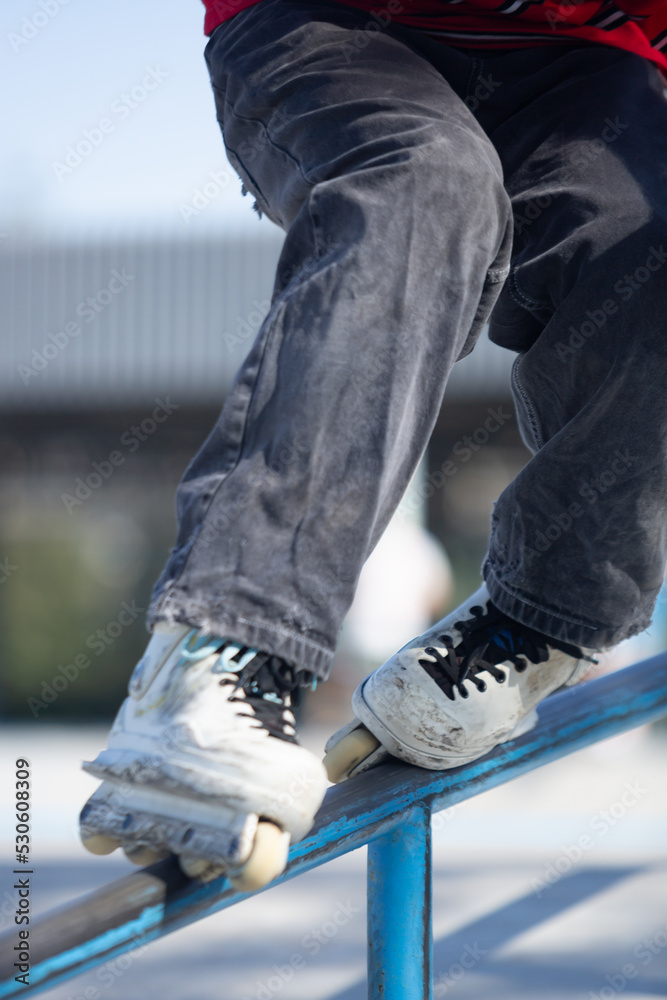 Roller blader grinding on handrail. In line skater grind on rails in skatepark outdoor
