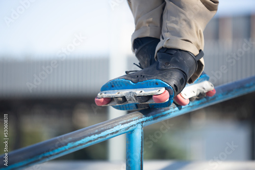 Fototapeta Naklejka Na Ścianę i Meble -  Inline skater grinds on rail in skatepark. Roller blader grinding on handrail.