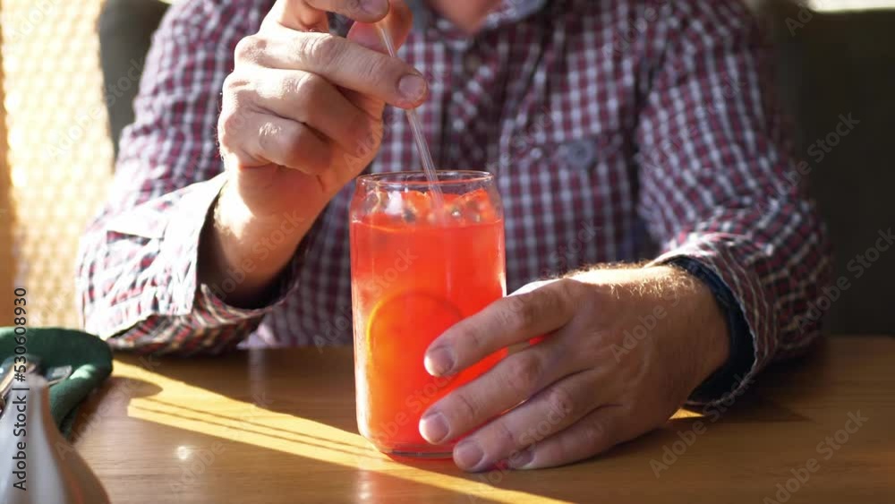 Orange lemonade with ice, a cooling drink. A man mixes a drink in a glass jar in a restaurant. Orange lemonade with ice, a cooling drink. A man mixes a drink in a glass jar in a restaurant.