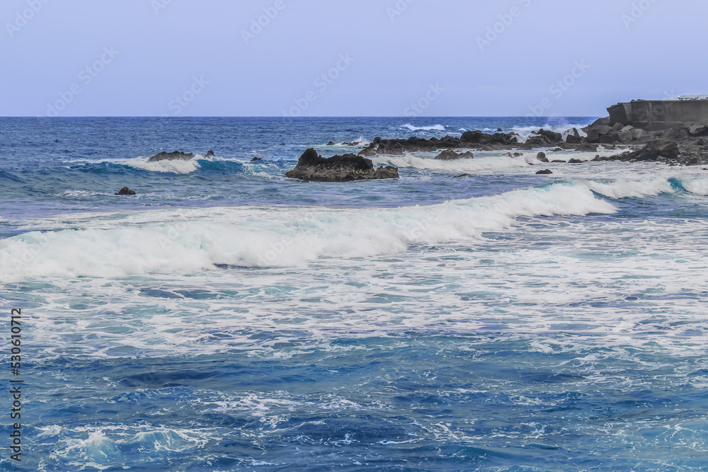 Large foamy wave crashes on rocks in the ocean. Storm on the sea - seascape