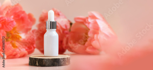 White glass dropper bottle with silver cap on woooden podium with peonies in soft focus as background. Pipette with fluid hyaluronic acid, serum, retinol. Natural cosmetics, health care, beauty mockup