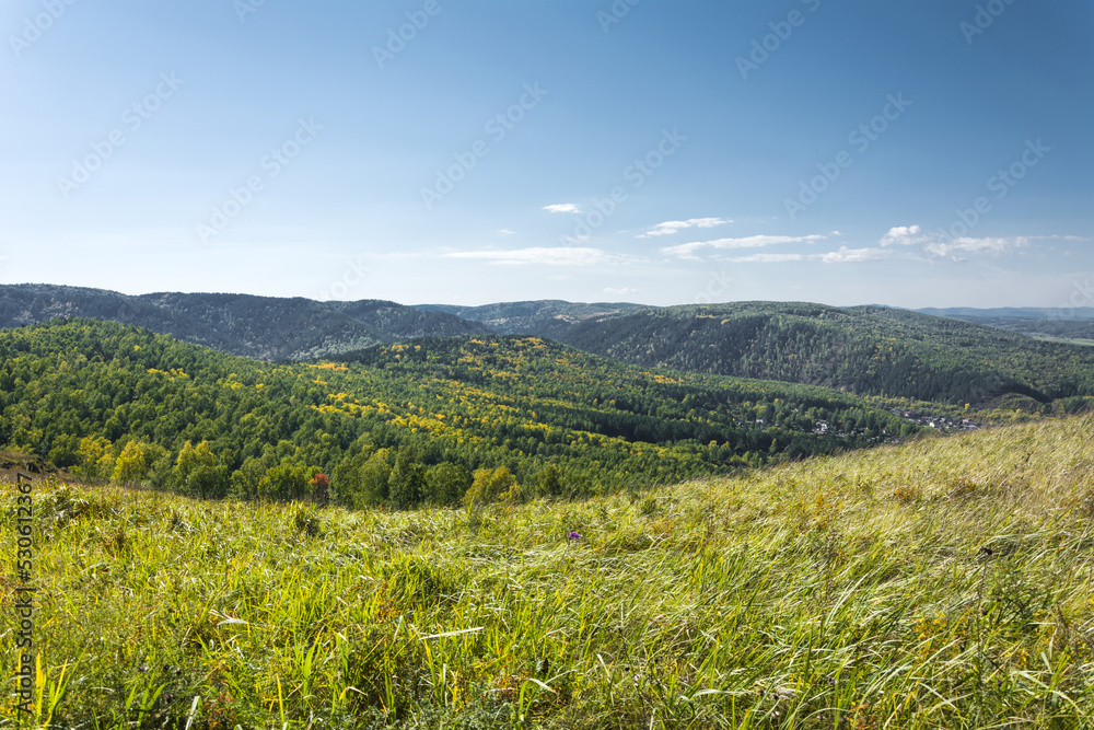 Landscape of the first days of autumn withered grass in the foreground and a panorama of mountains and blue sky with clouds