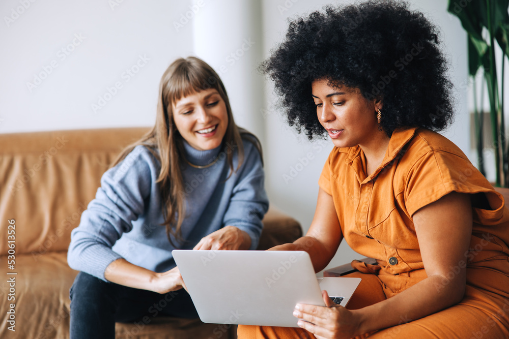 Businesswomen having a discussion while using a laptop in an office Businesswomen having a discussion while using a laptop in an office