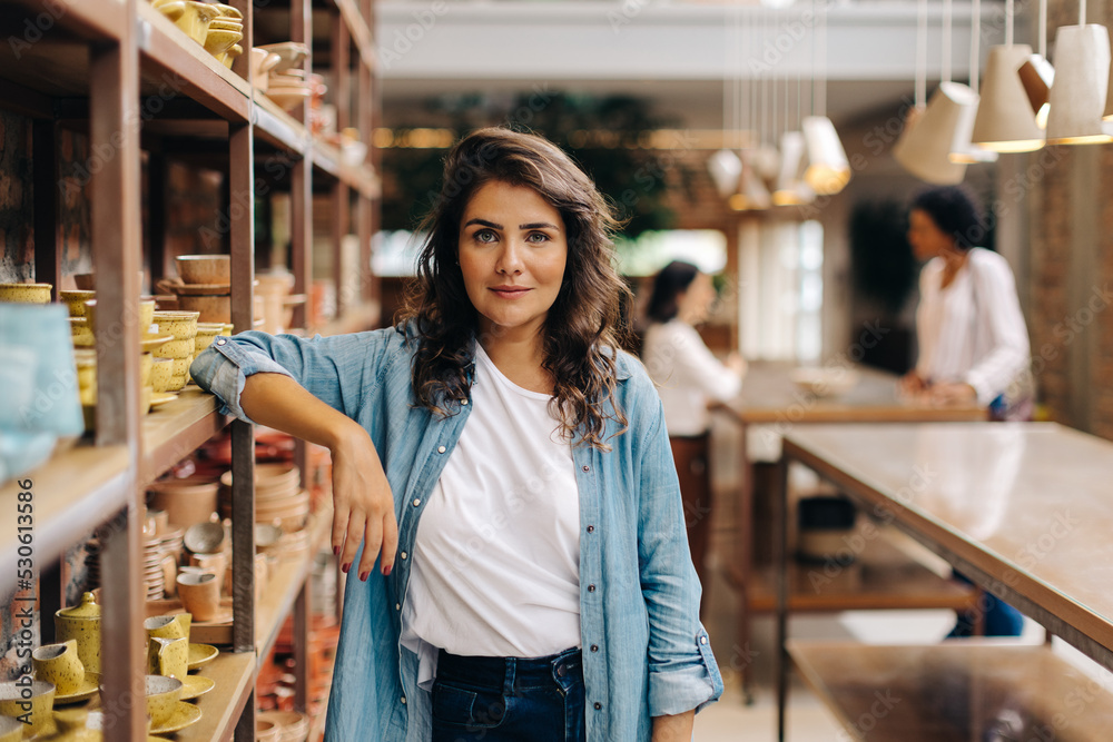 Confident young woman looking at the camera in her ceramic store Confident young woman looking at the camera in her ceramic store