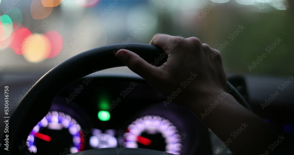 Female driver holding car steering wheel driving at night in city