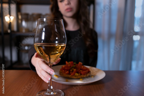 Young woman sitting in the kitchen with a glass of wine. Teen alcoholism concept  alcohol addiction problems among women
