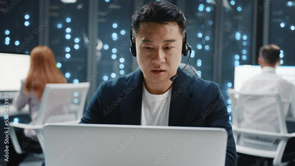 Close up asian IT developer administrator wearing headset speaker using laptop computer. Server room technicians. Teamwork. Telecommunication. Close up asian IT developer administrator wearing headset speaker using laptop computer. Server room technicians. Teamwork. Telecommunication.