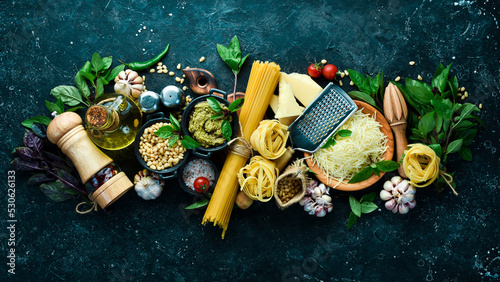 Preparation of pasta with pesto sauce and sun-dried tomatoes. Italian traditional cuisine. On a black stone background background.