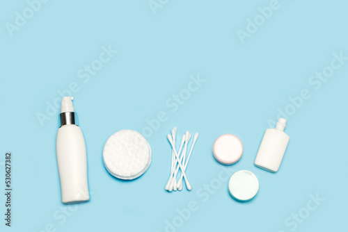 Discos de algodón, bastoncillos para limpieza facial junto a una botella de agua micelar sobre un fondo celeste pastel liso y aislado. Vista superior y de cerca. Copy space photo