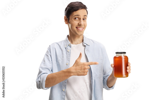 Happy young man holding a jar of honey and pointing