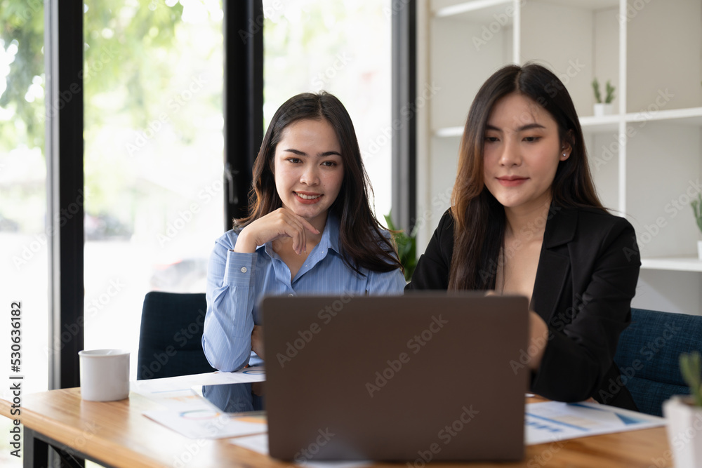 two young asian woman working on laptop computer at office.