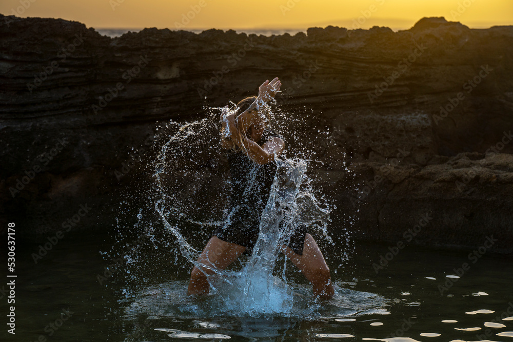 Obraz premium middle-aged woman dancing and throwing water in the air, Maioris beach, llucmajor, Majorca, Balearic Islands, Spain