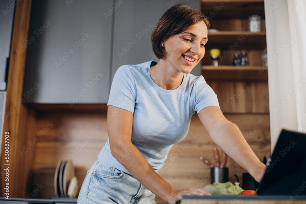 Woman watching cooking lessons on tablet at the kitchen Woman watching cooking lessons on tablet at the kitchen