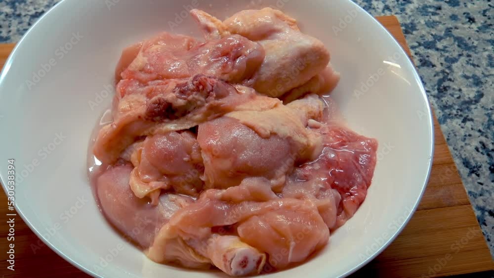 A person is spicing fresh chicken meat. A person is spicing fresh chicken meat.