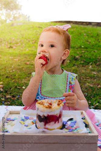 girl enjoying strawberry shortcake in the park during a family picnic