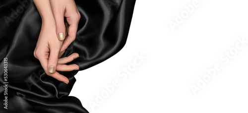Female hands with glitter gold nail design. Glitter golden nail polish manicure. Female model hands with black fabric on black background.