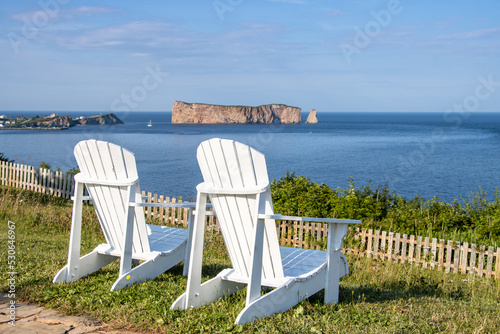 Two Adirondack chairs and Perce rock in background. Gaspe peninsula, Quebec, Canada photo