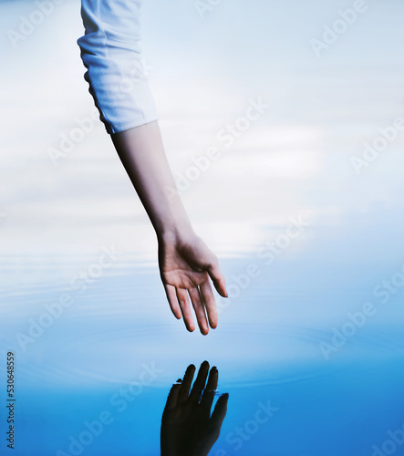 The hand of a woman in a white turtleneck stretches in the clear water of the lake, leaving circles on the water. The purity of the ocean water. Fresh water.