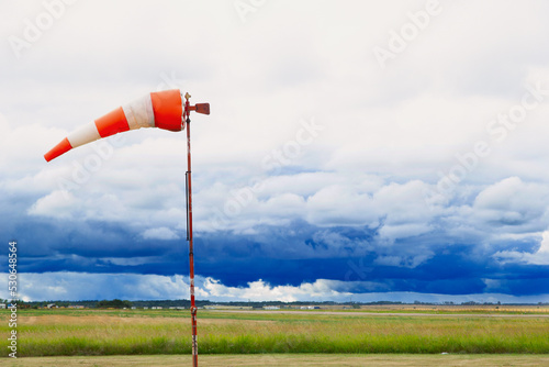 Horizontally flying windsock or wind vane against stormy sky