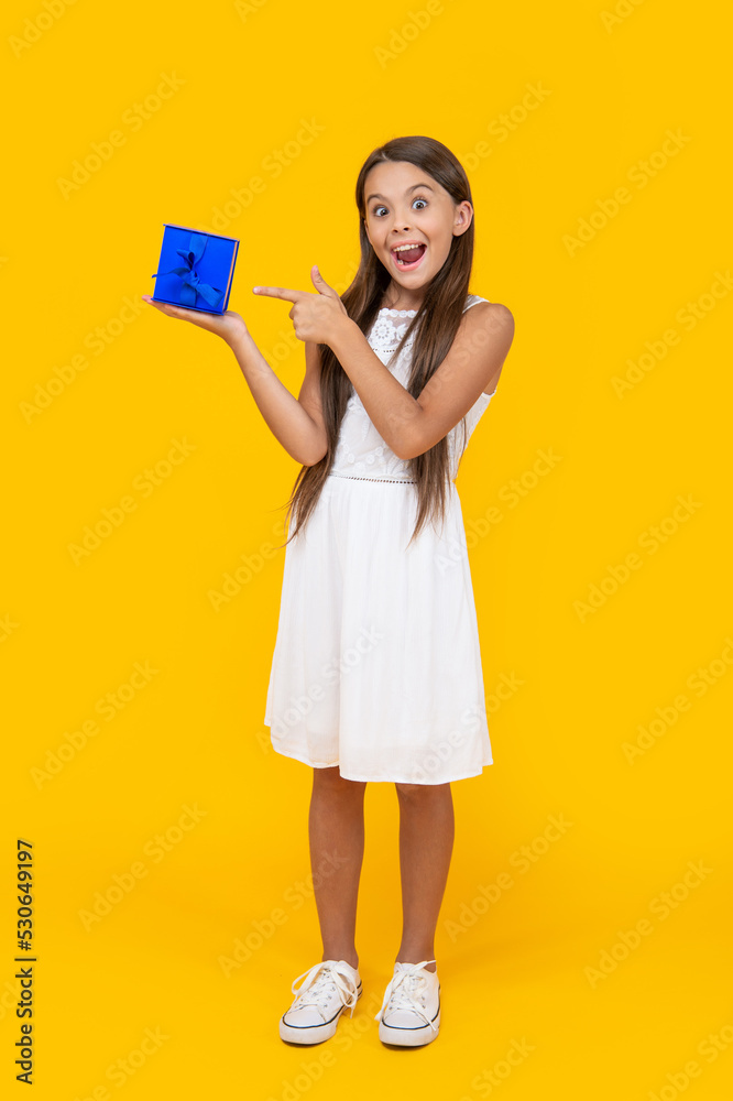 amazed teen girl point finger on present box on yellow background amazed teen girl point finger on present box on yellow background