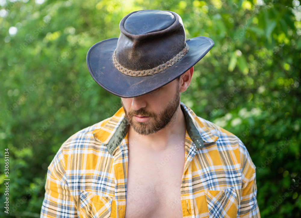 man in cowboy hat look down. sexy cowboy in checkered shirt. western cowboy wearing hat