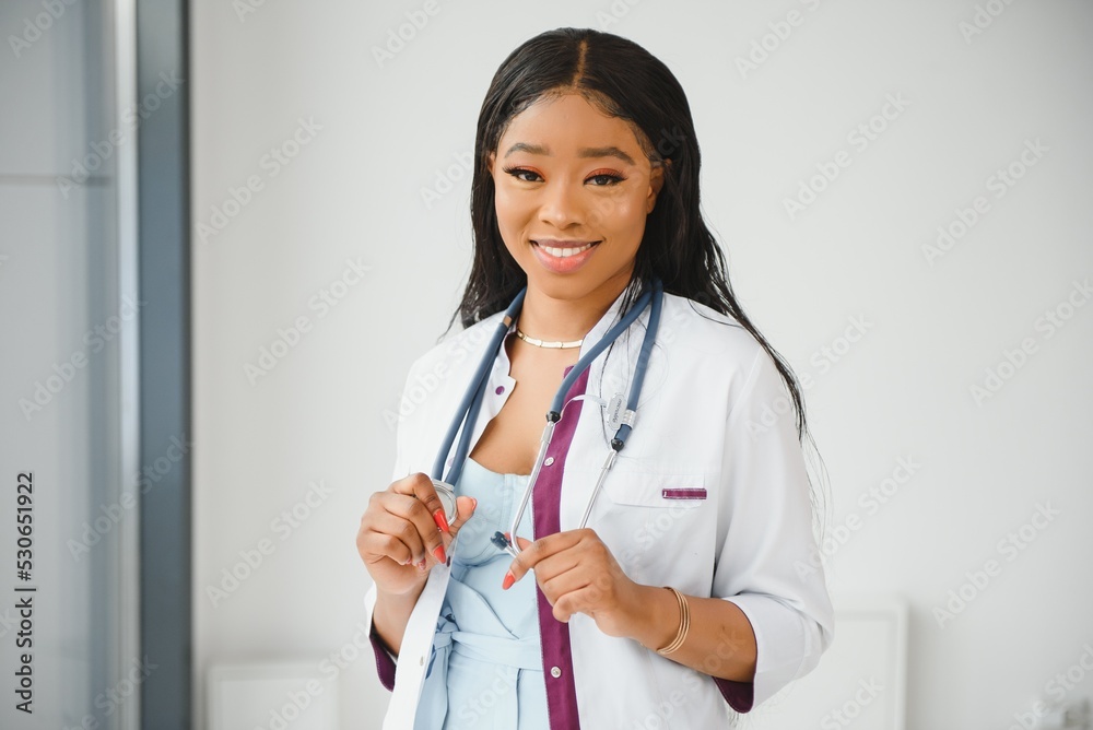 Closeup headshot portrait of friendly, smiling confident female healthcare professional with lab coat, arms crossed holding glasses. Isolated hospital clinic background. Time for an office visit Closeup headshot portrait of friendly, smiling confident female healthcare professional with lab coat, arms crossed holding glasses. Isolated hospital clinic background. Time for an office visit