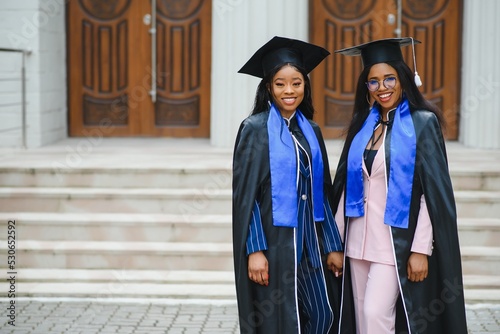 young graduates standing in front of university building on graduation day