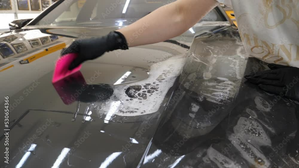 Close up to PPF installation process on a front headlight and hood. PPF