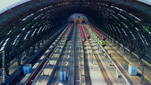 Aerial view of the station where trains arrive. An old arched structure made of metal and glass above the station poles. Tourism. Transport. Skyline with tall buildings. Italy, Milan, 09.2022 photo