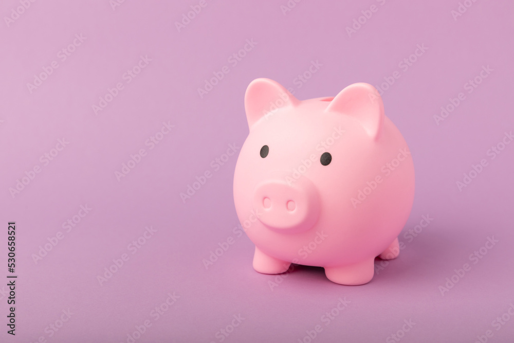 Piggy bank on a lilac texture background. Close-up. Space for copy. Flat lay. Savings and accumulation concept.