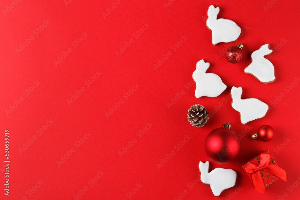 Delicious gingerbread in the form of a rabbit and Christmas decor on a red background. copy space. Symbol 2023 Delicious gingerbread in the form of a rabbit and Christmas decor on a red background. copy space. Symbol 2023