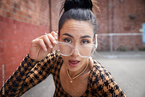 Asian woman looking over her eye glasses with an expression of skepticism. 