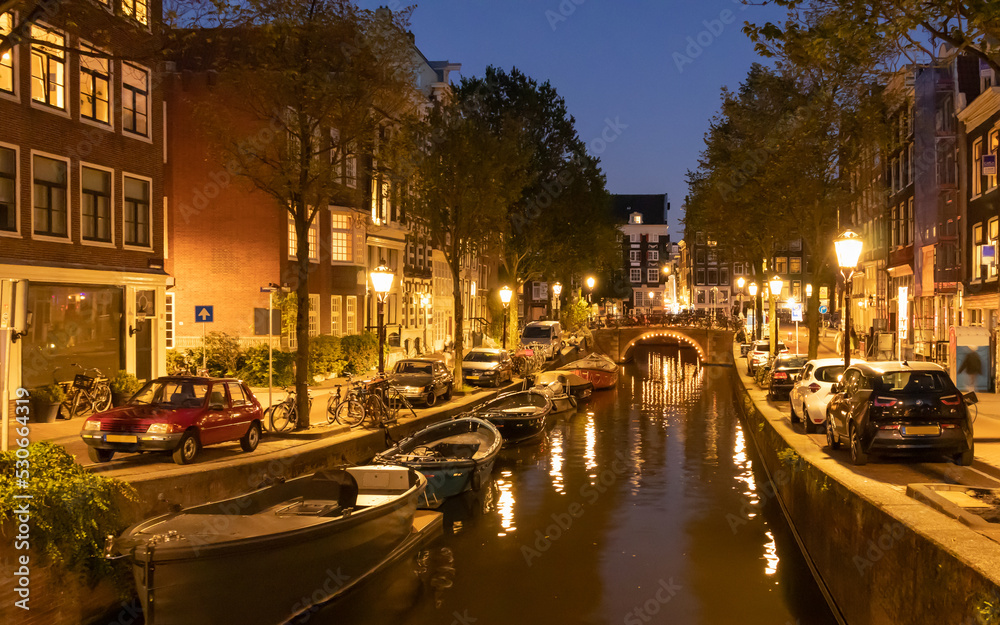 Typical old Amsterdam houses  and chanels with boats at night in Netherlatnds